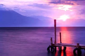 Sun setting on Lake Atitlan, with stream of red sunlight reflected on water surface.