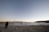 A tourist walks near the steam let off from fumaroles at the Uyuni salt flats, Bolivia.