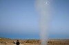 A tourist watches steam being let off by a fumarole at the Uyuni salt flats, Bolivia.