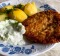 Traditional polish breaded pork chop called kotlet schabowy, salad with cucumbers and sour cream called mizeria and ...