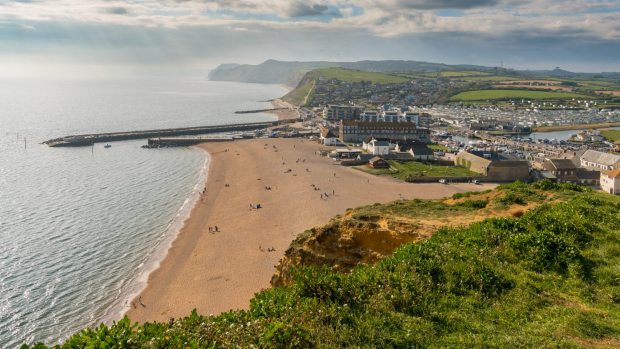 West Bay, Dorset, England, UK - April 23, 2017: View from the cliffs on the beach, with people on the beach and the River Brit on the right SunSept29Ten - Traveller Ten - 10 of the best British TV locations - text Steve McKenna
iStock image for Traveller. Re-use permitted.